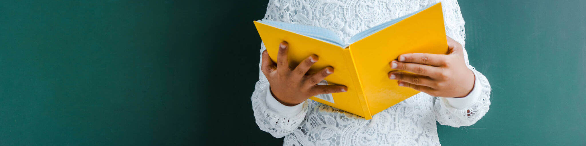 Panoramic Shot Of Kid Holding Yellow Book On Green