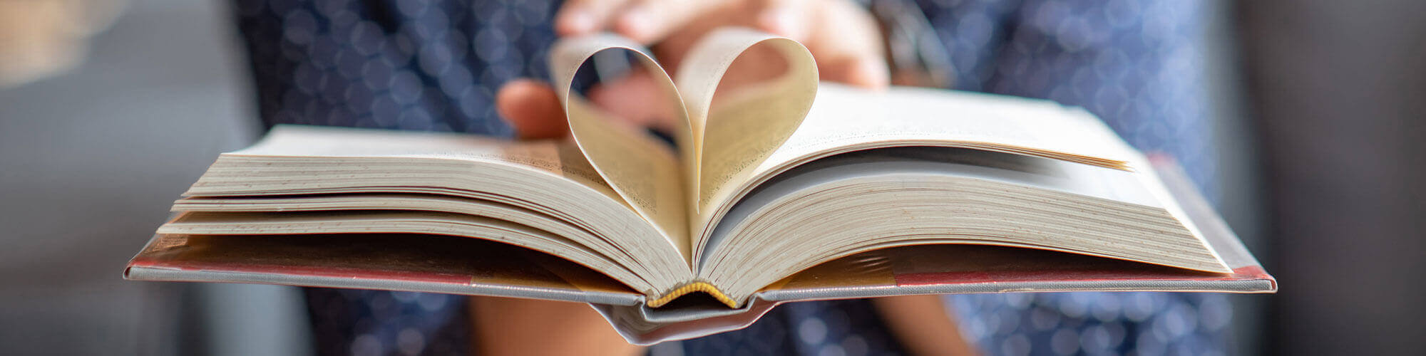 Male Hand Holding Book With Heart Shape Page Folded